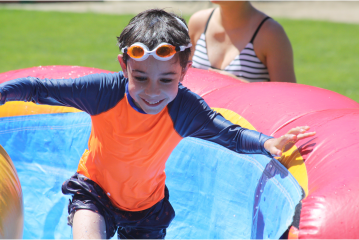 Camper in goggles running up a slip n slide