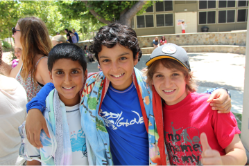 Three camper friends taking a photo with arms around each other outside