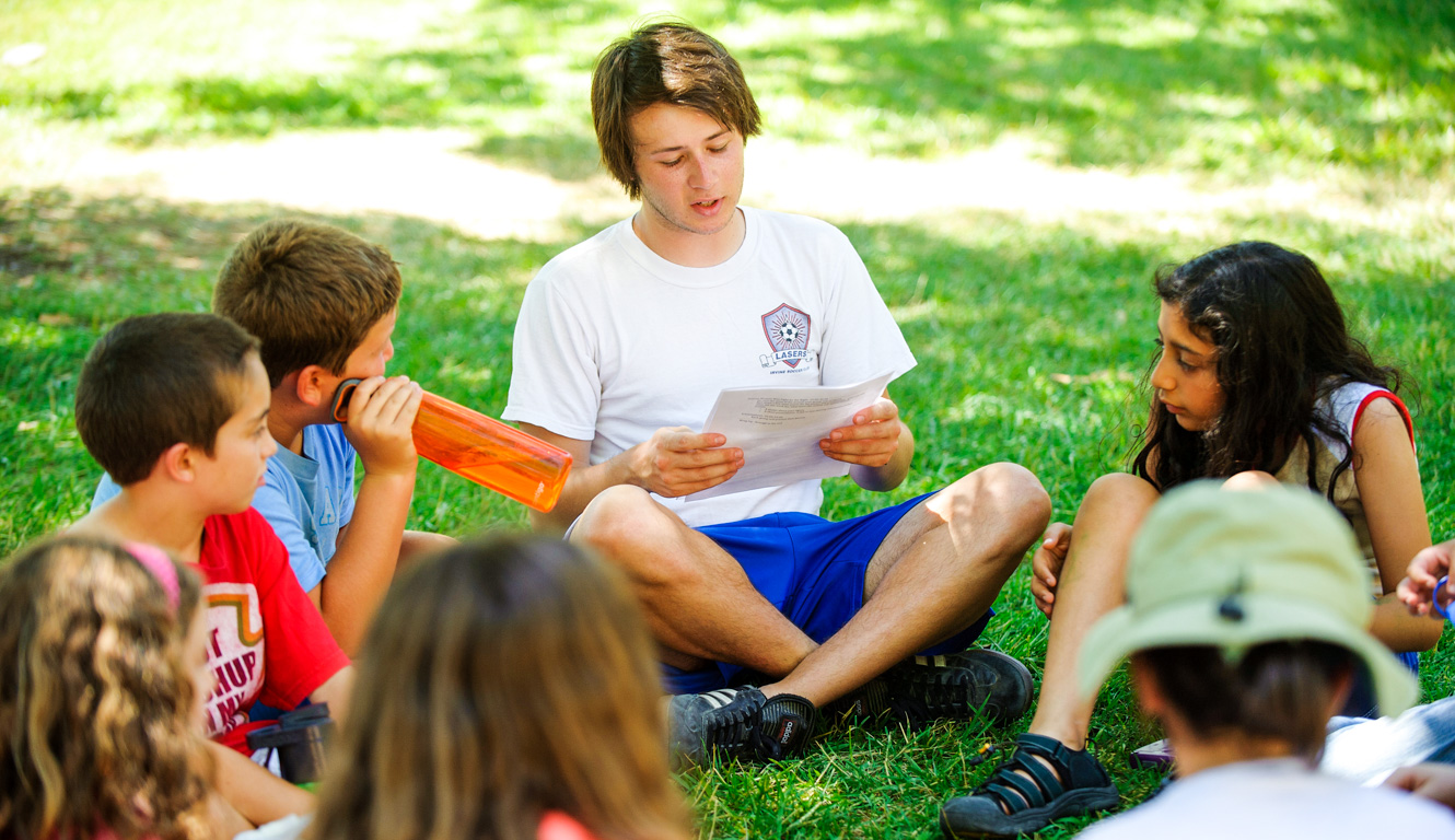 Counselor reading to campers on the grass