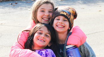 Campers in coats and hats hugging for a photo