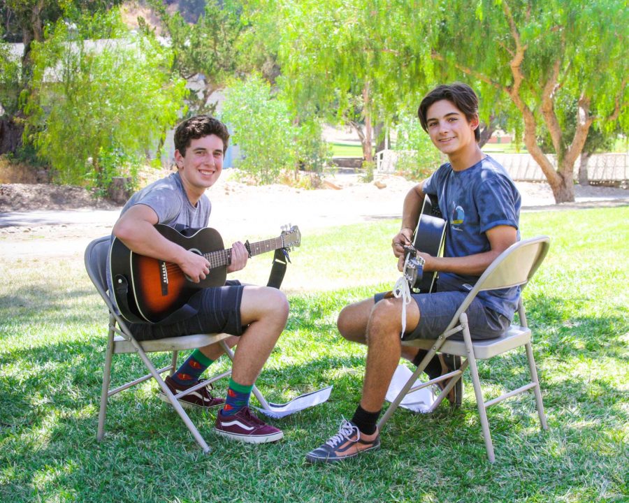 Two campers playing guitar together