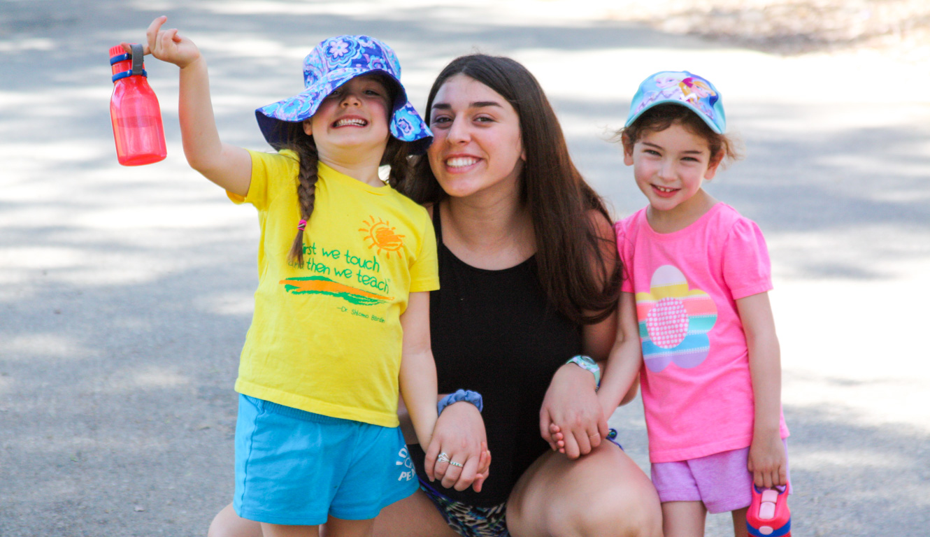 Counselor smiling with campers for a photo