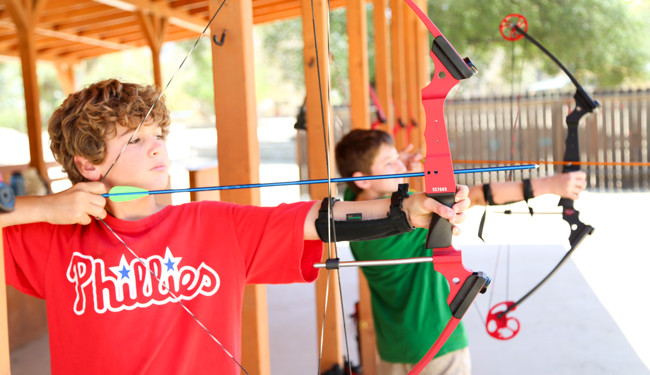 Camper pulling back the bow in an archery class