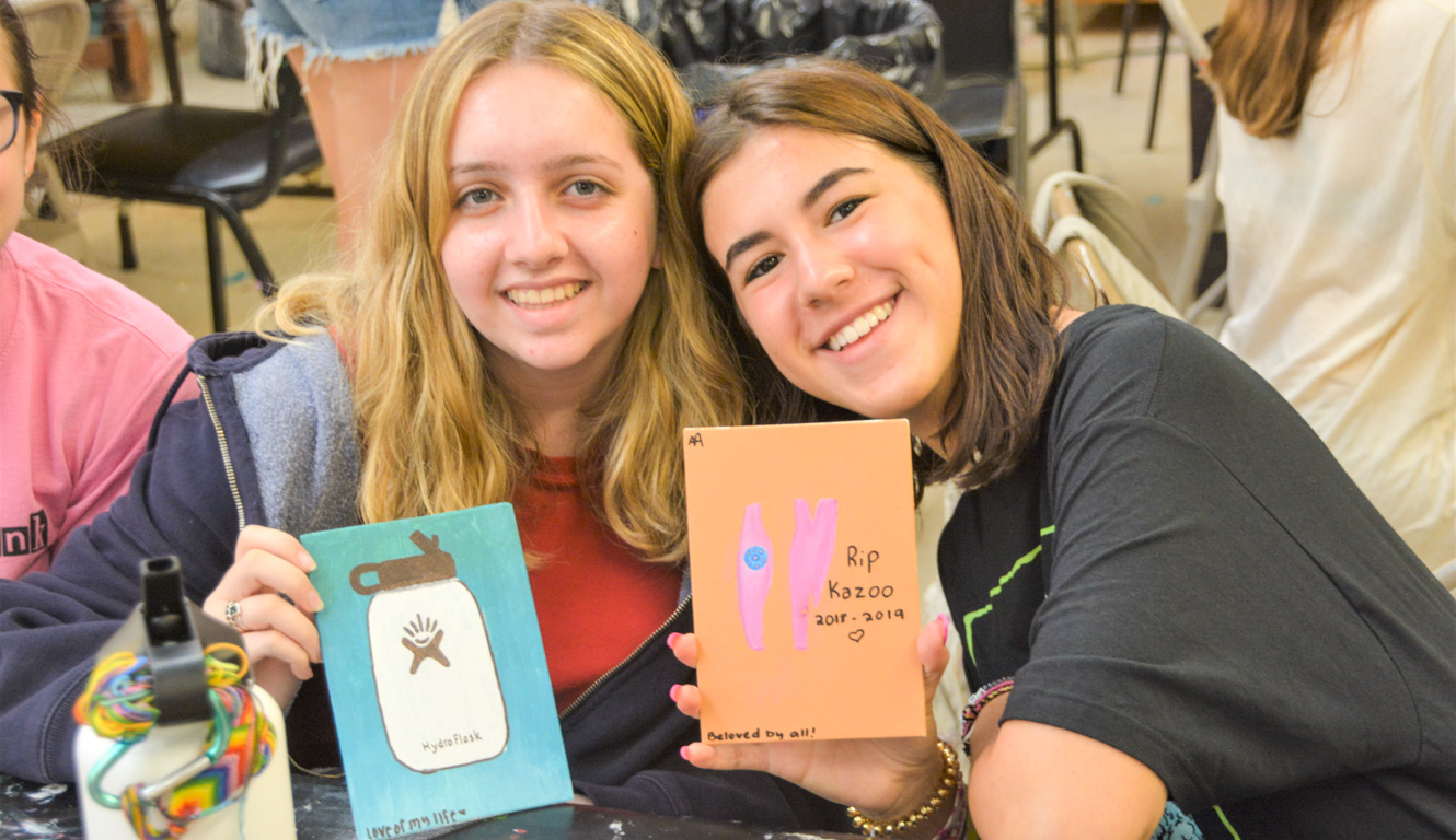 Two friends smiling holding up their craft project