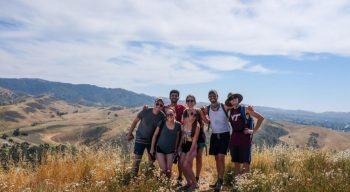 Group of students in a field on a hill taking a group photo