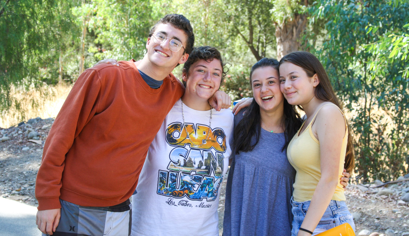 Group of teens with arms around each other smiling for a group photo