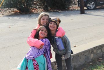 Campers in coats and hats hugging for a photo