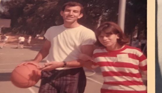 woman in striped shirt and man in t shirt holding a basketball at camp in the 1960s