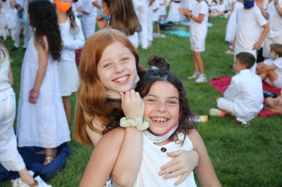 Two young camp age girls embracing and smiling