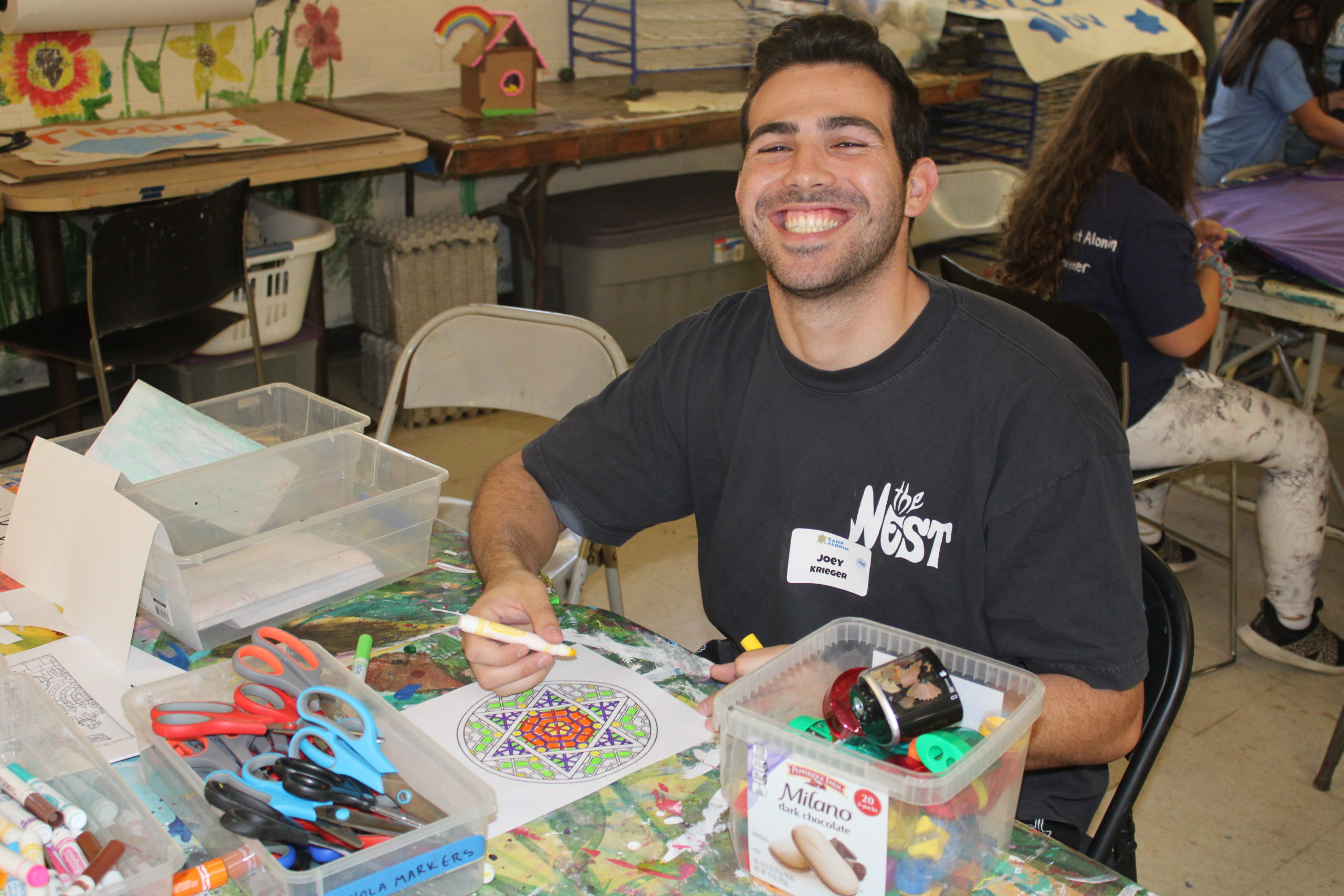 young man in his mid twenties in a t shirt doing an art project where he is drawing